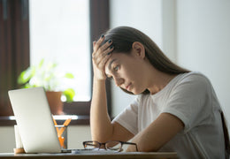 Woman staring at laptop screen and looking stressed