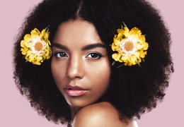 Curly-haired woman with two yellow flowers in her hair