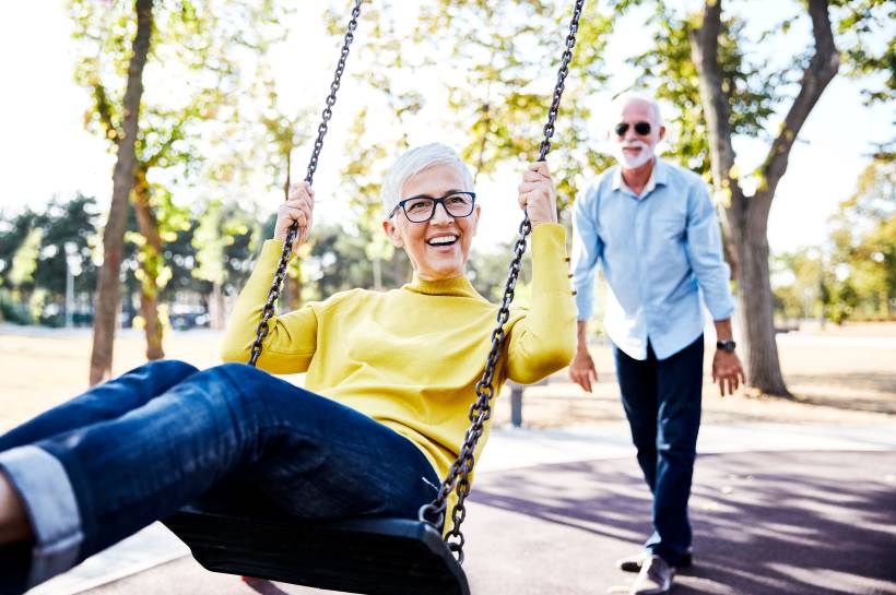 A man is pushing his wife on a swing