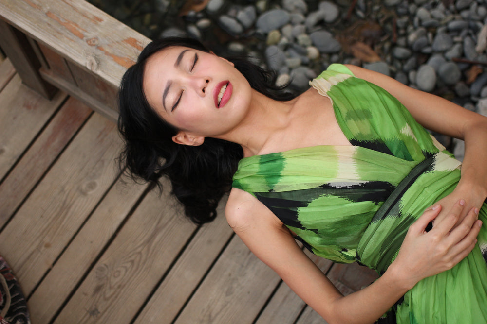 Woman in a green dress lying down with her eyes closed.