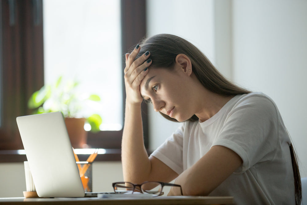 Woman staring at laptop screen and looking stressed