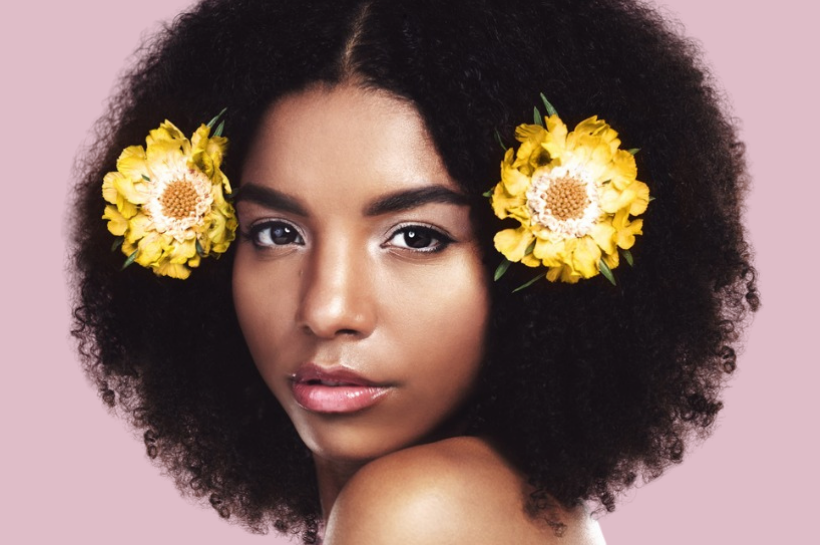 Curly-haired woman with two yellow flowers in her hair